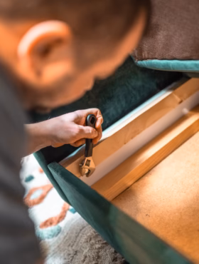 Man disassembling sofa furniture mechanism at home using furniture wrench. DIY Assembling Furniture concept.